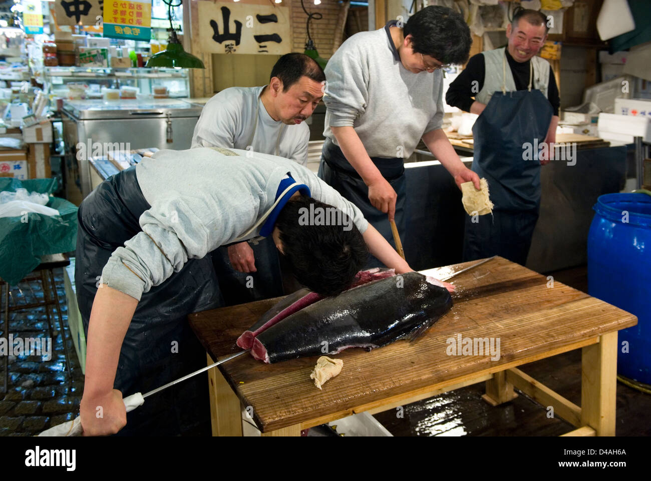 Fishmonger cuts fresh raw tuna with giant sharp knife at Tsukiji Stock