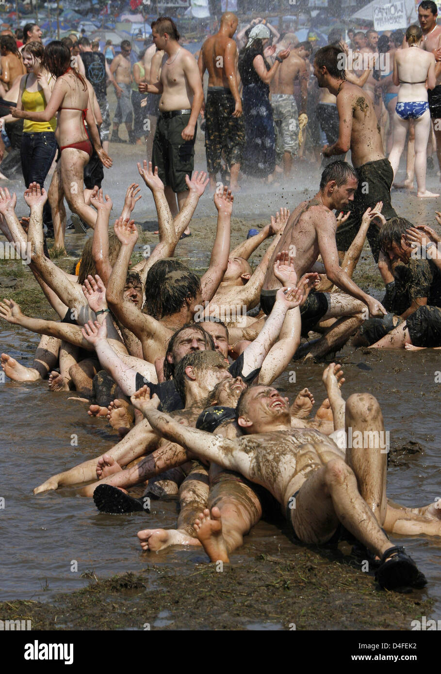 Teenagers roll in a puddle of mud at the rock festival 'Haltestelle