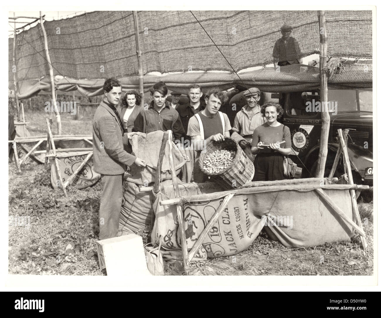 Photograph of hop pickers, Kent, 1950's. A man holds the measuring