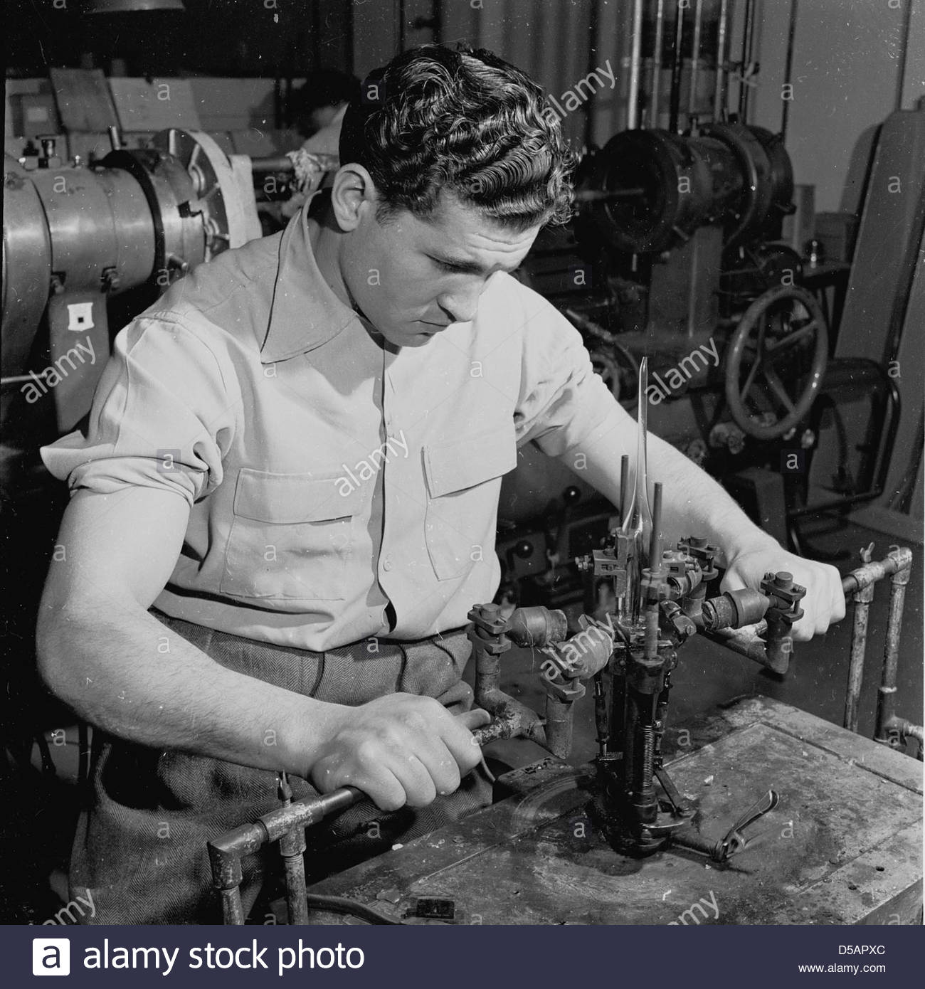 Historical 1950s.Industry. An engineer checking the connection of Stock