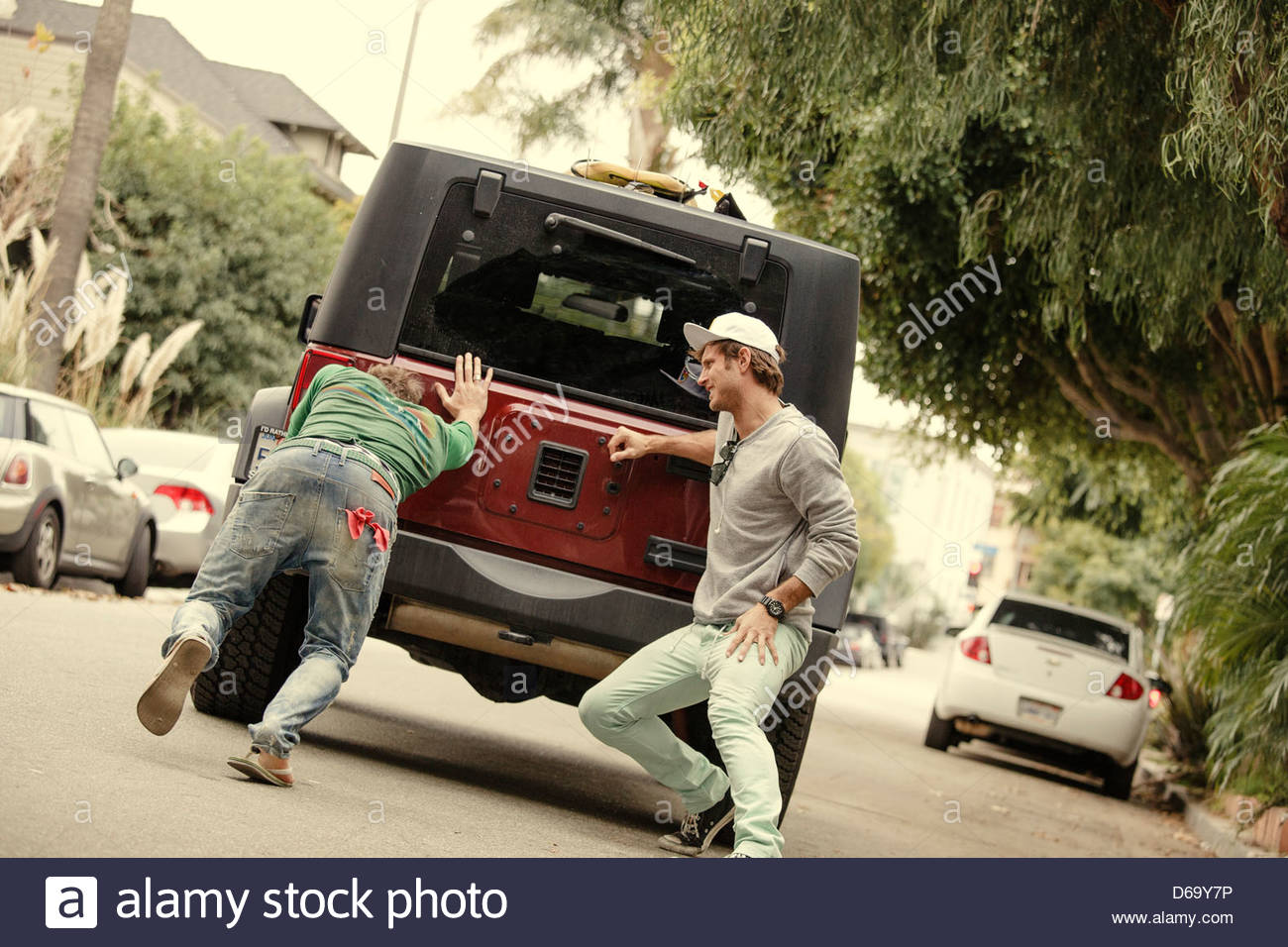 Men pushing broken down car on street Stock Photo, Royalty Free Image