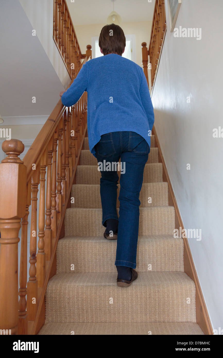 Everyday scene of a senior woman walking up stairs holding onto a Stock