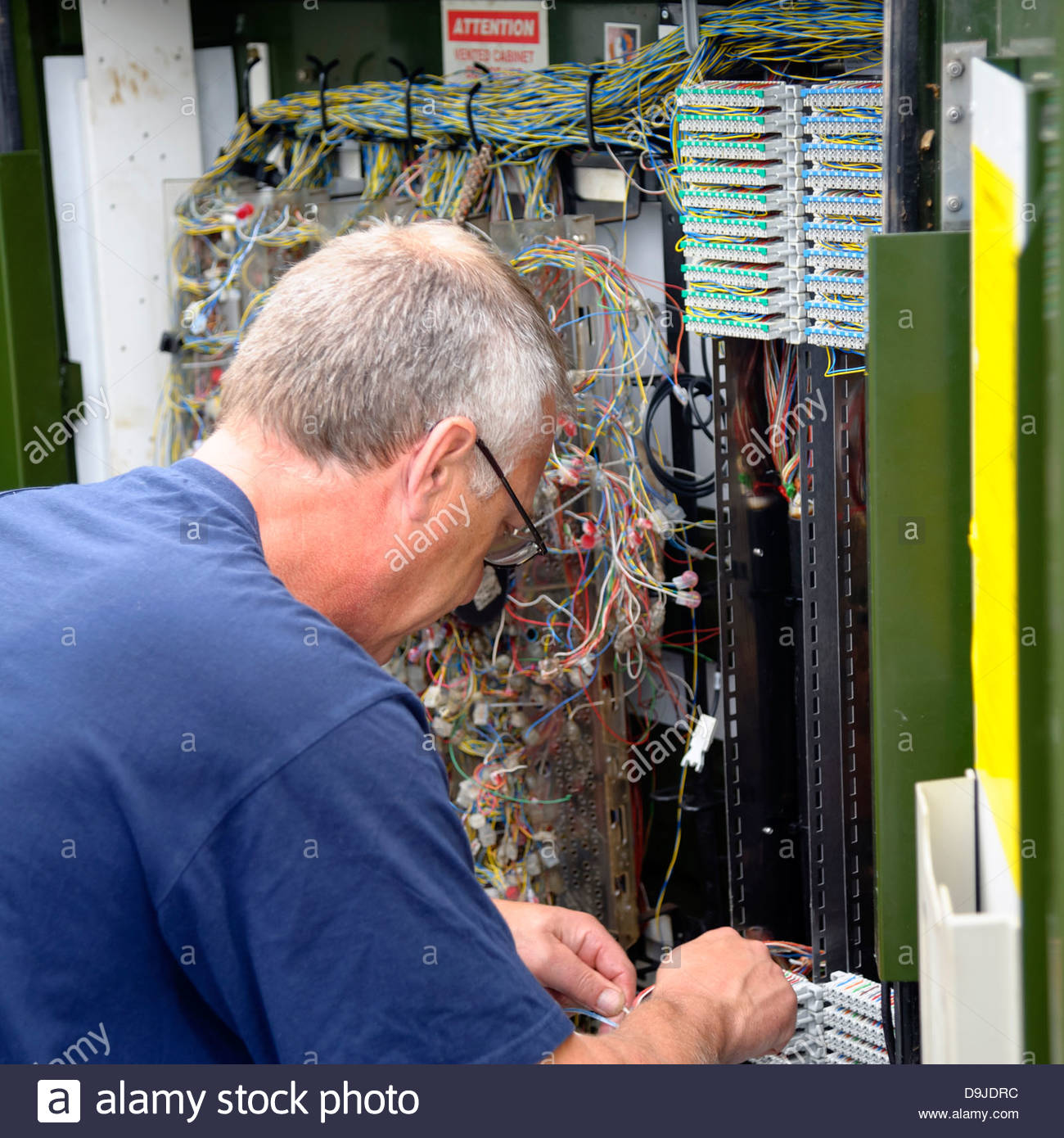 Telephone engineer connecting wires in a BT roadside Stock
