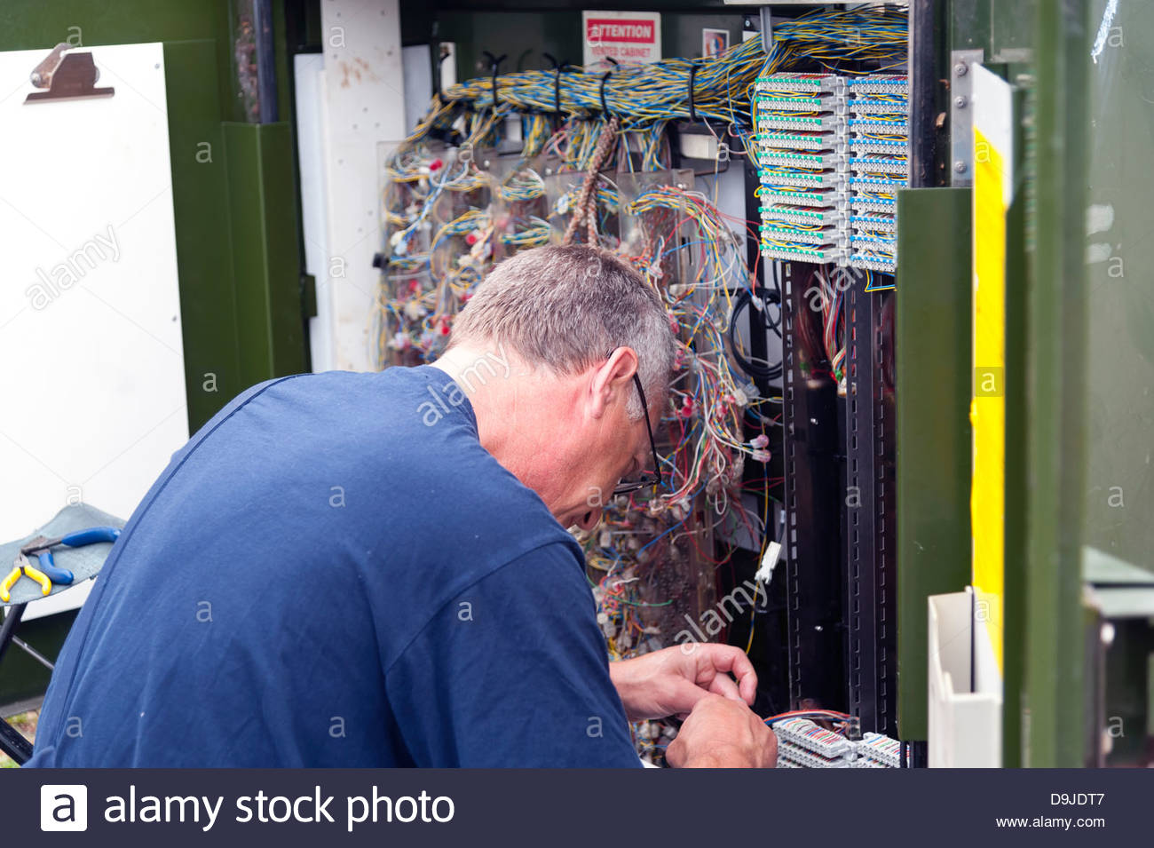 Telephone engineer connecting wires in a BT roadside Stock