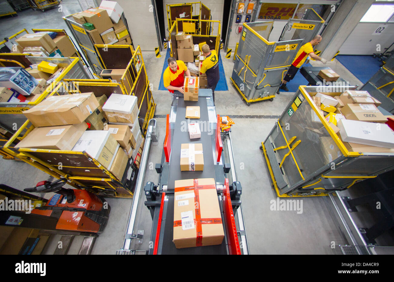 Staff of the Deutsche Post DHL shipping service place parcels on a