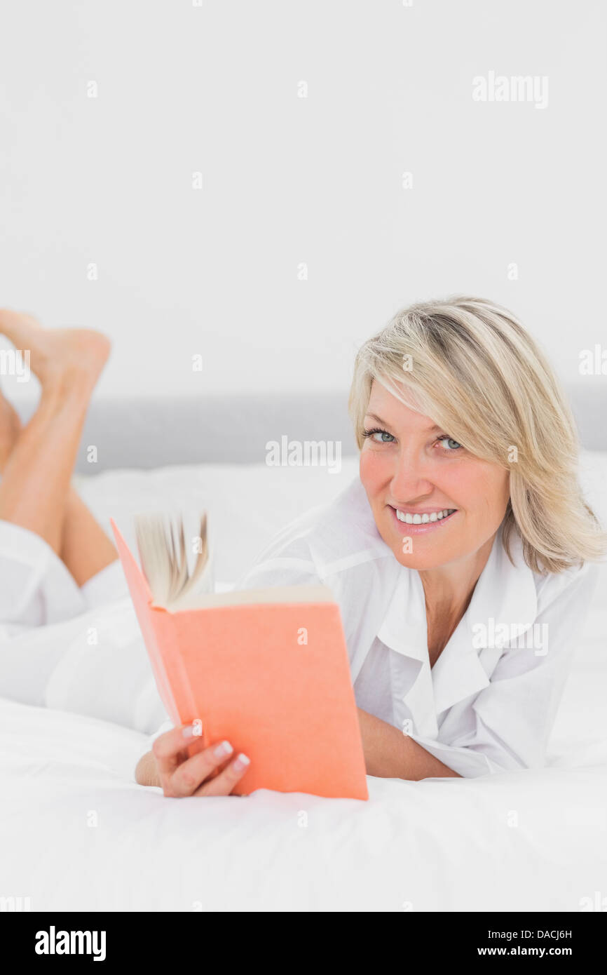 Blonde Woman Reading A Book Lying On Bed Stock Photo Alamy