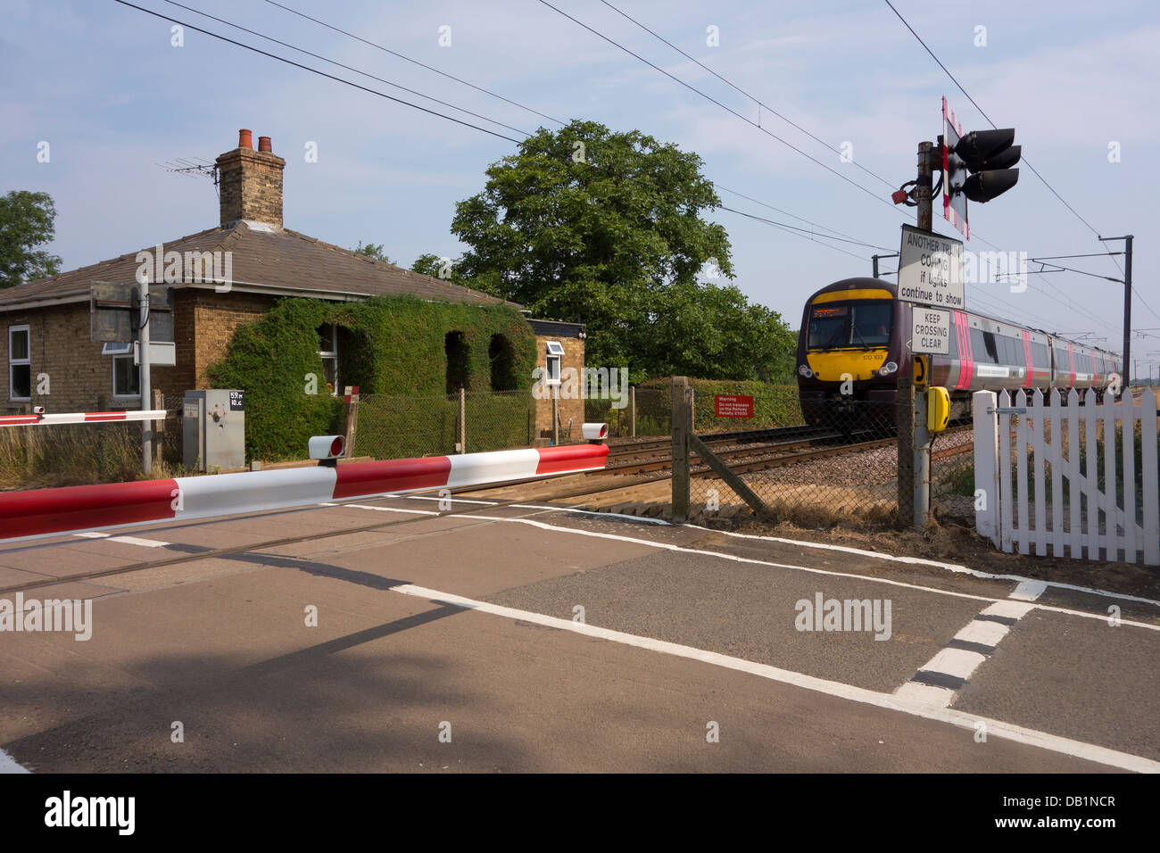 Train approaching level crossing Milton Cambridgeshire England Stock