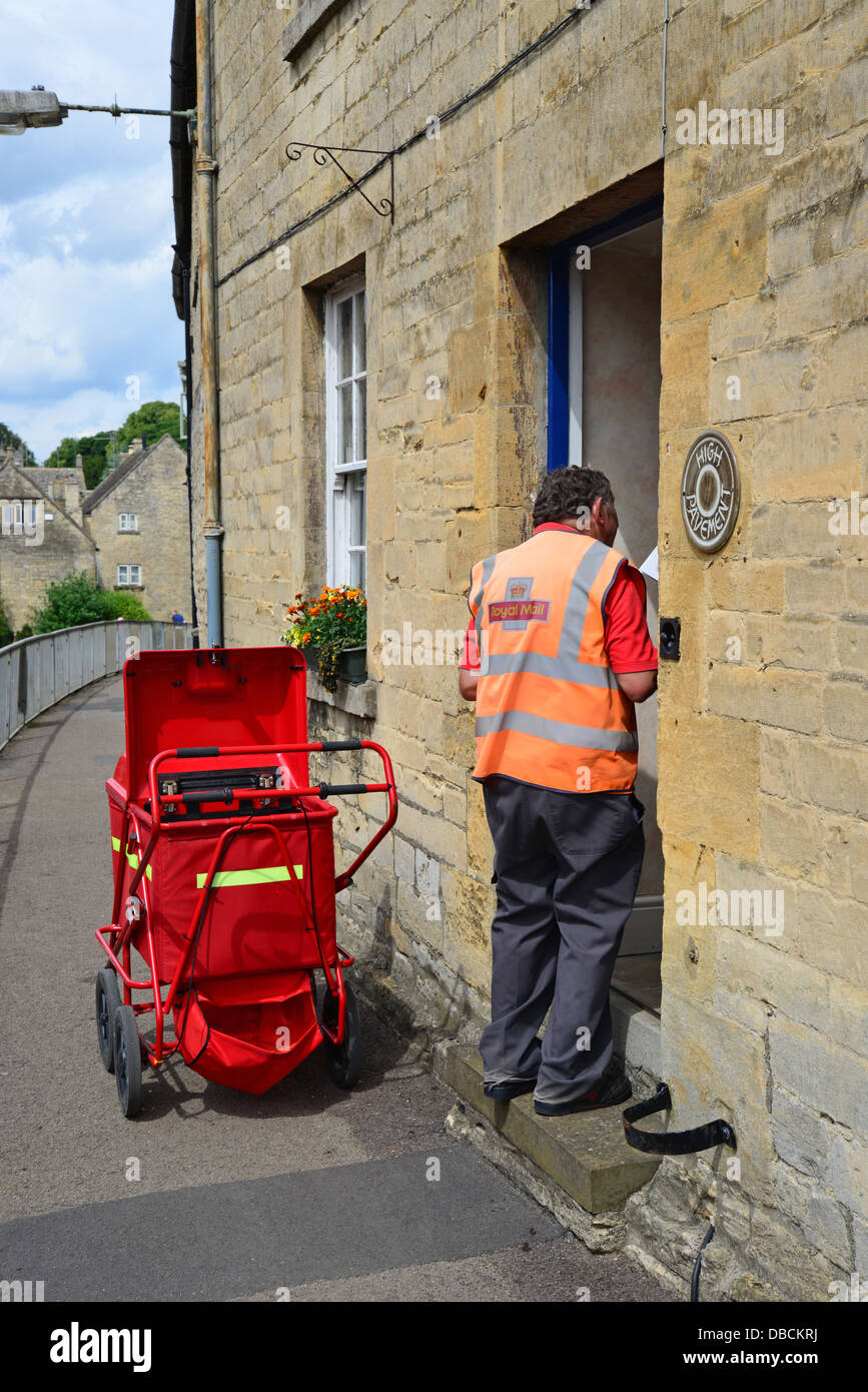 Royal Mail postman delivering mail to house, High Street, Northleach