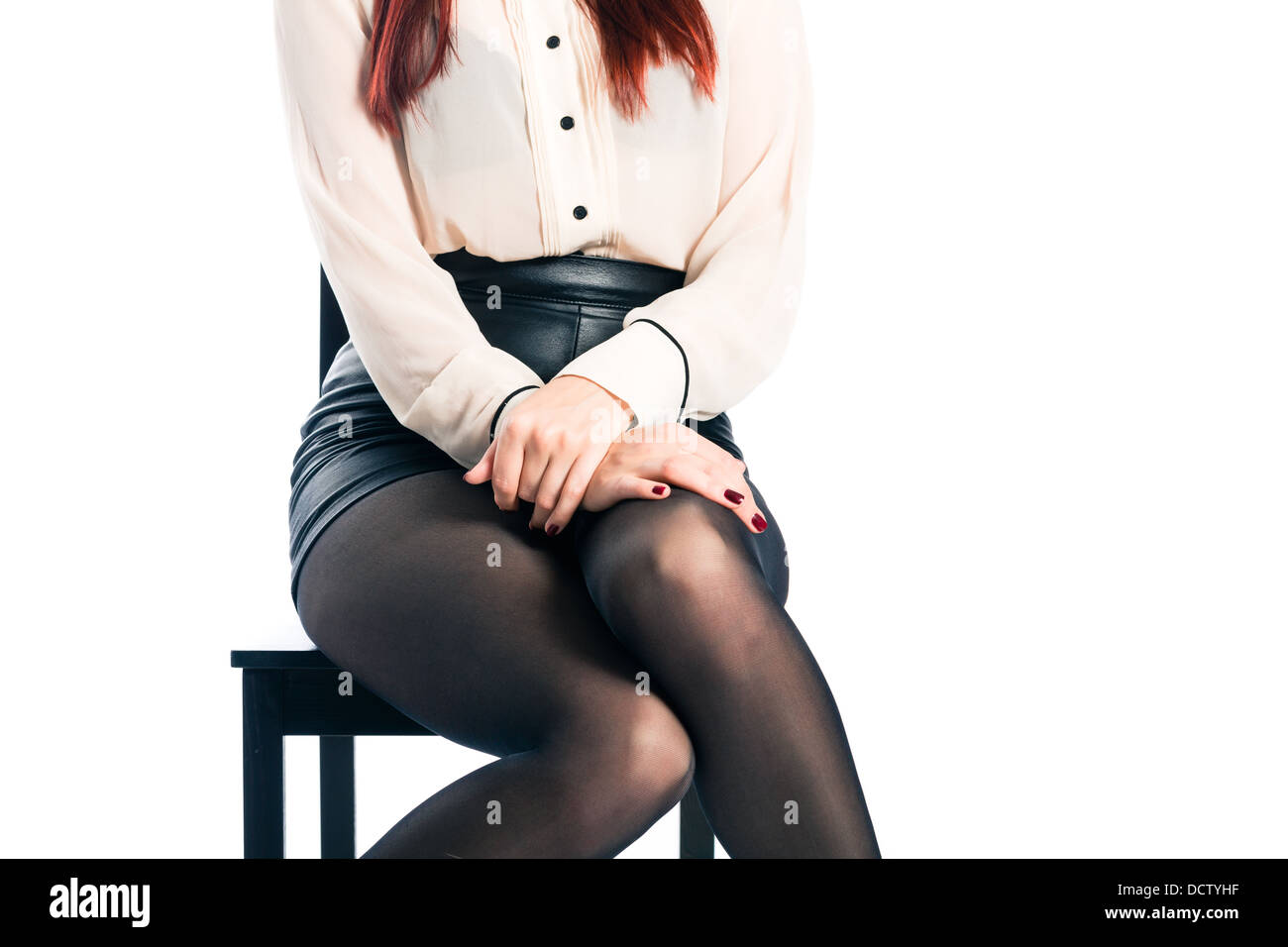 Young woman sitting on a chair, only the legs and the lap is showing