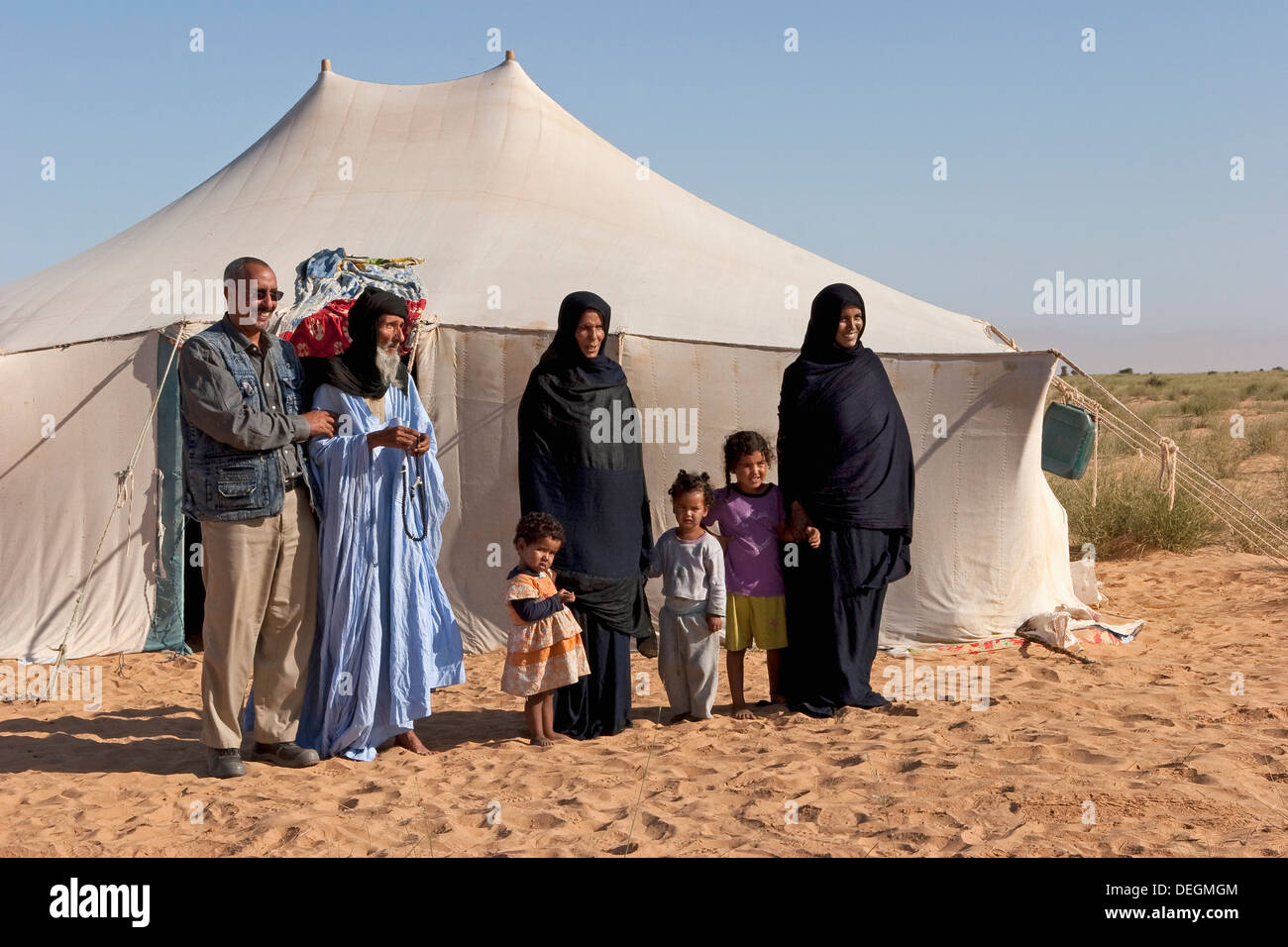 Islamic nomadic family outside their home tent with area community