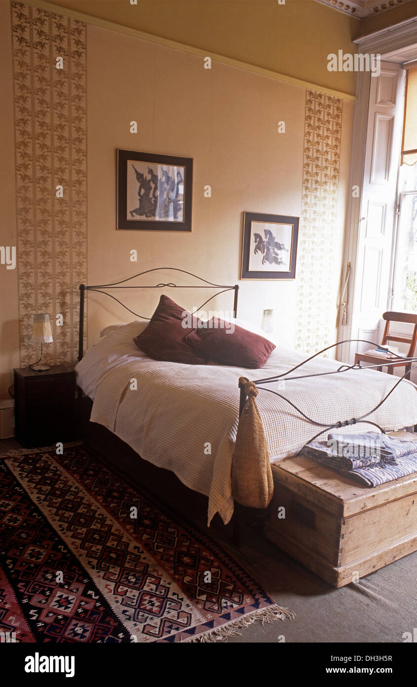 Old pine chest at the foot of metal bed with white bed ...