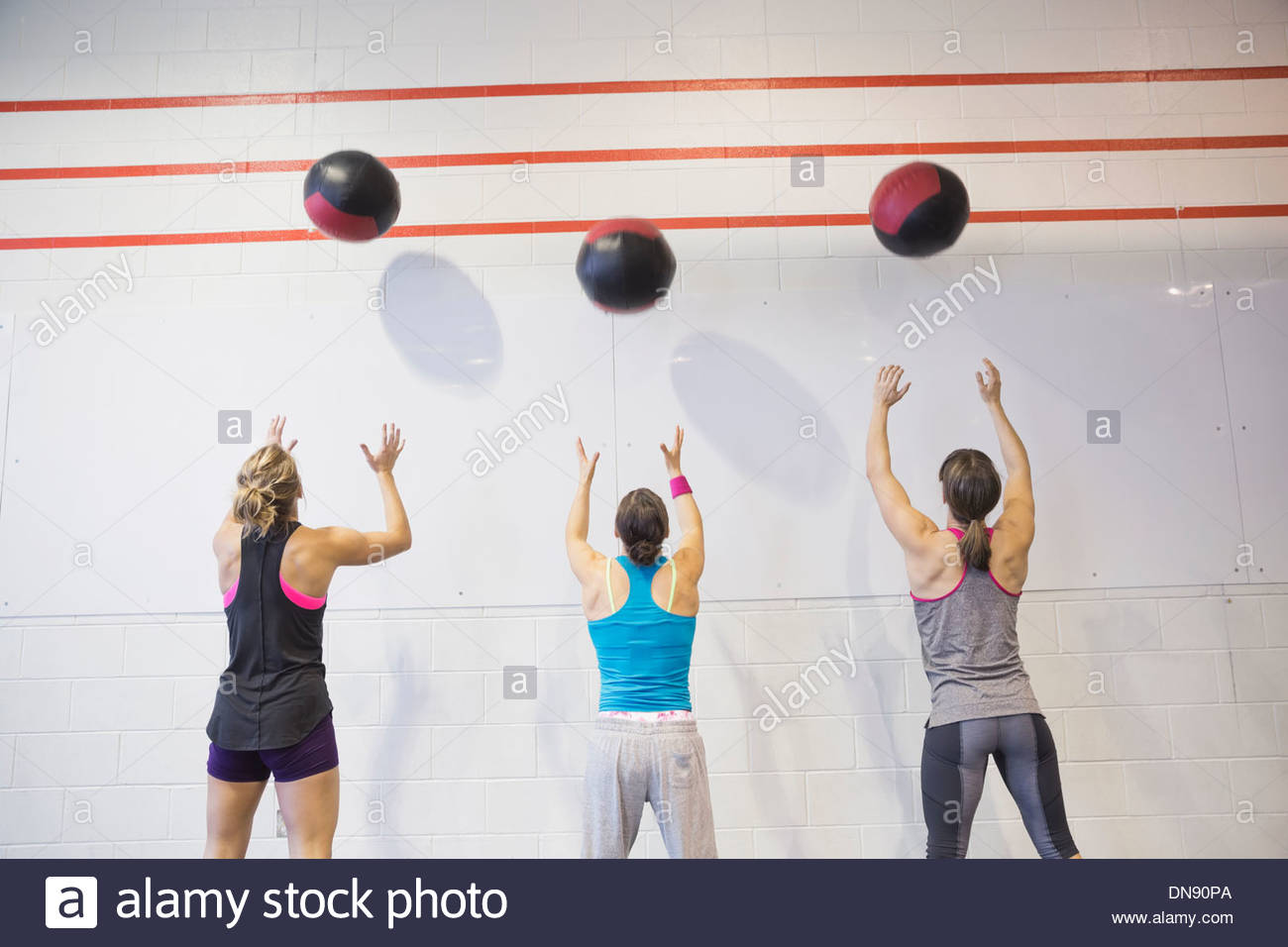 Women throwing medicine balls against wall Stock Photo, Royalty Free