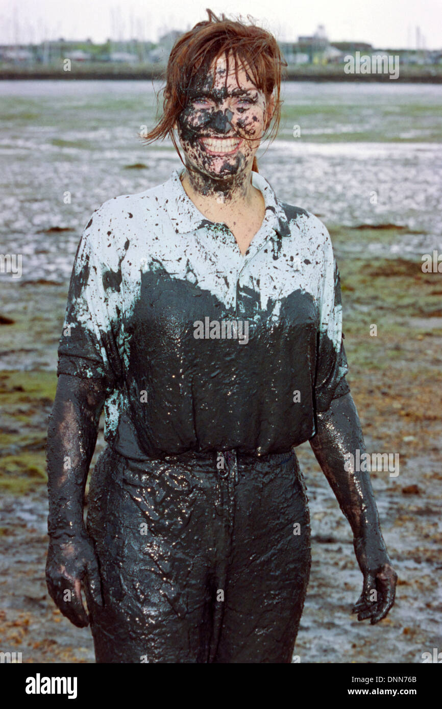 smiling woman covered in filth during traditional game of mud Stock