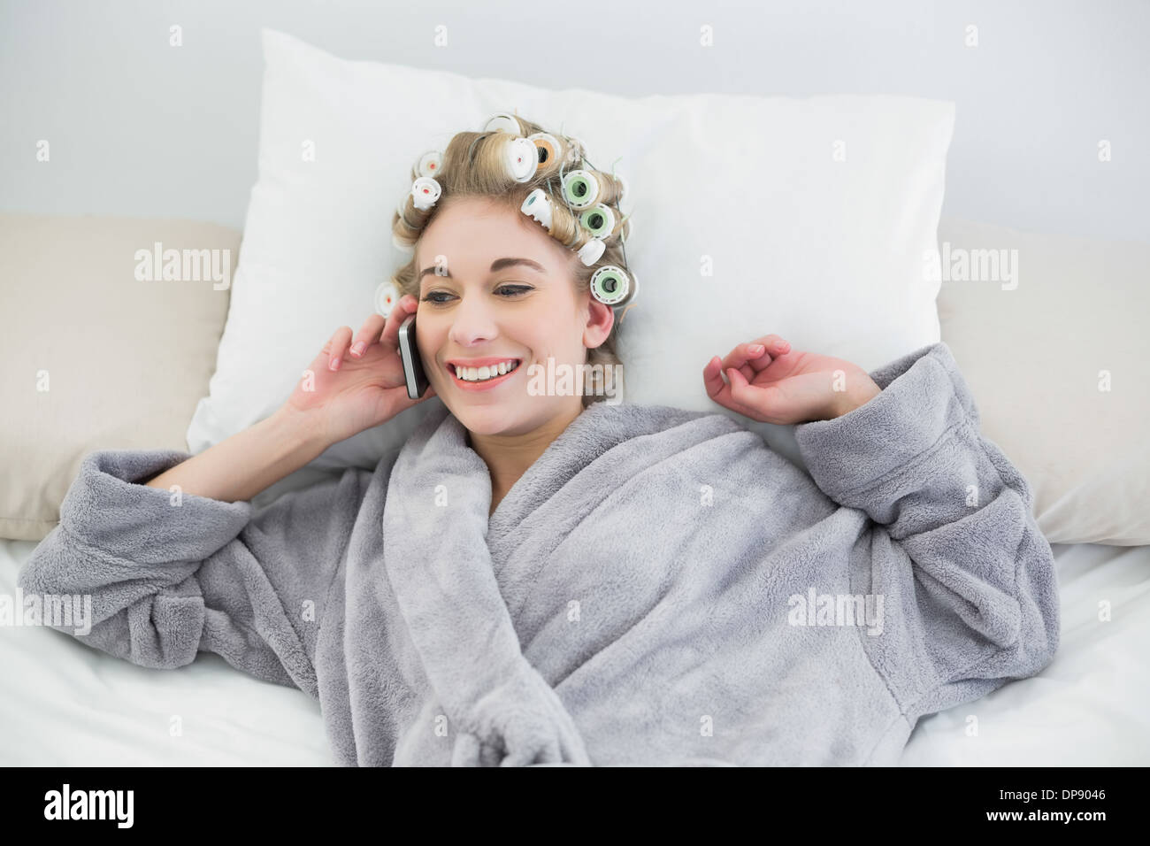 Delighted Relaxed Blonde Woman In Hair Curlers Making A Phone Call