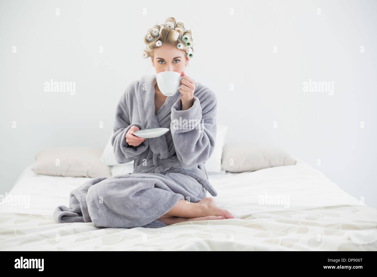 Attractive Relaxed Blonde Woman In Hair Curlers Drinking Coffee Stock