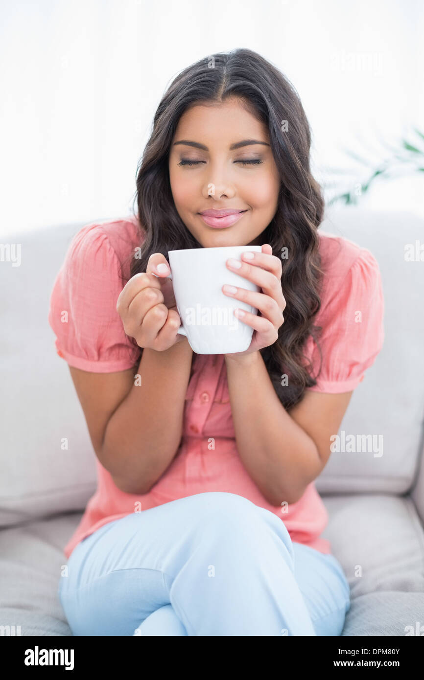 Pleased Cute Brunette Sitting On Couch Holding Mug Stock Photo Alamy