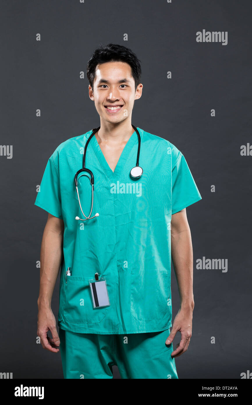 Portrait of a Male Asian doctor wearing Green Scrubs. Dark Grey Stock