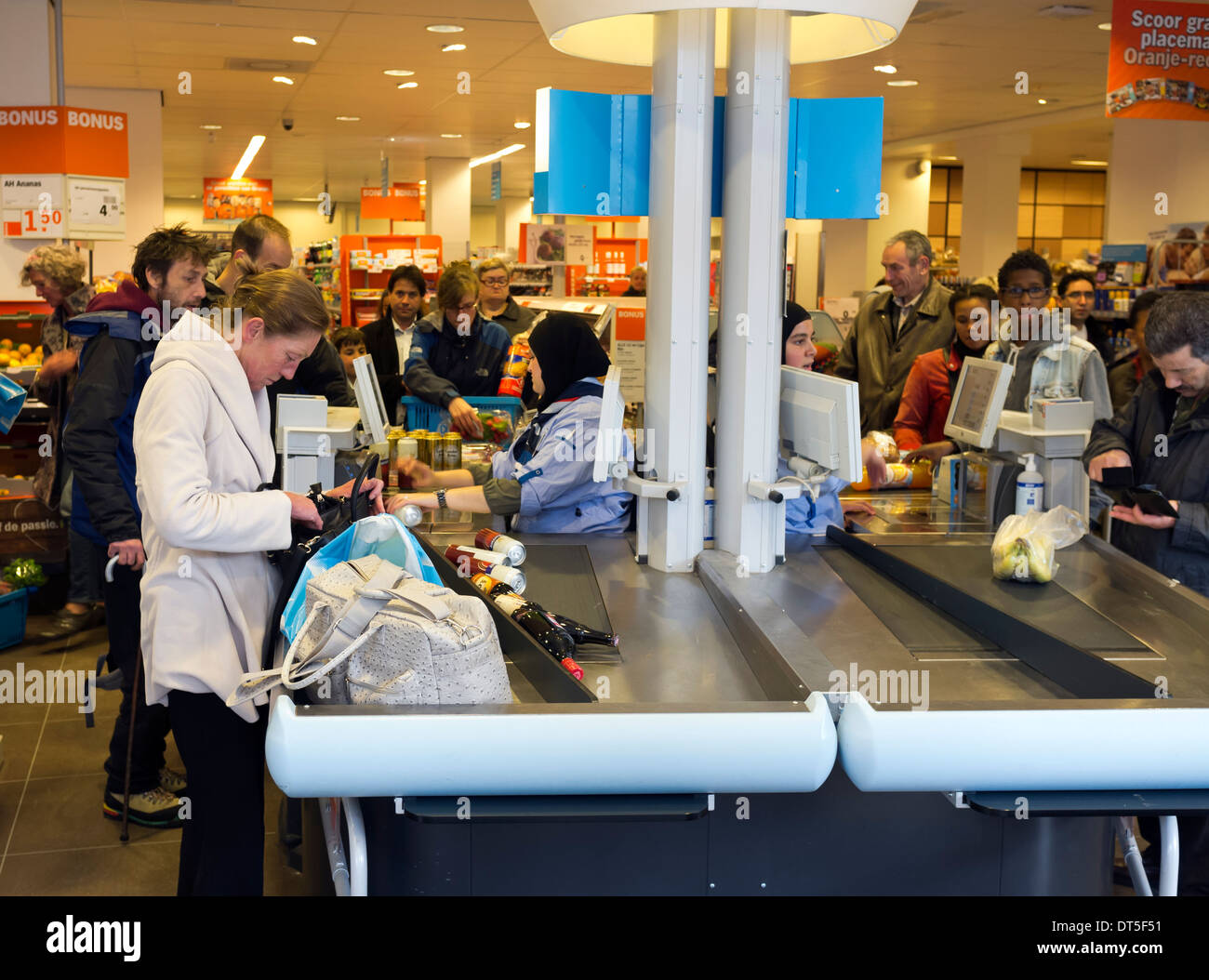 Queue of people and shoppers at a supermarket checkout till at the