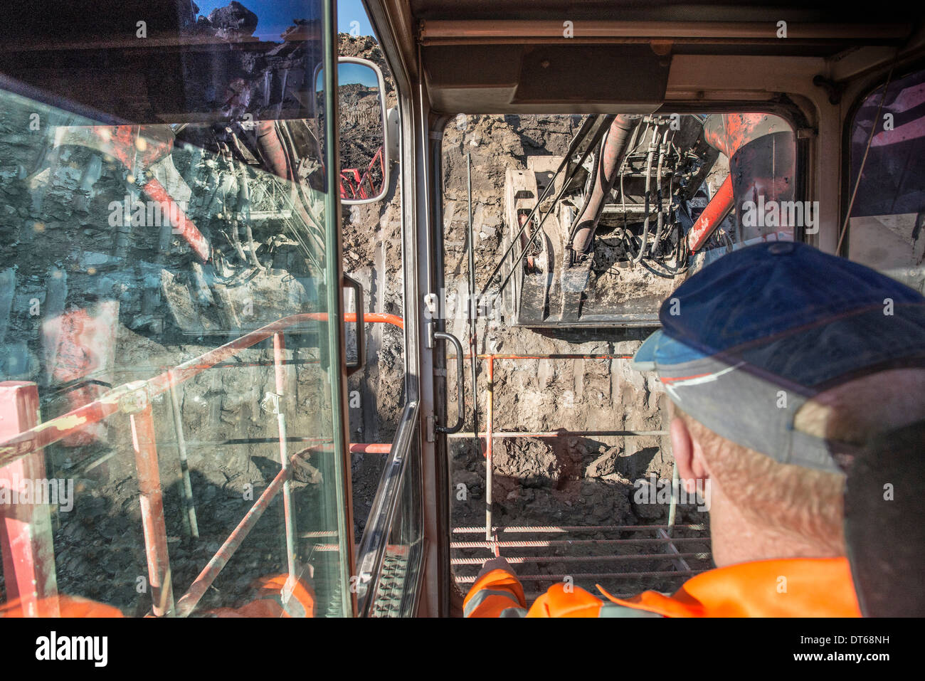 Excavator driver in digger cab at surface coal mine Stock Photo