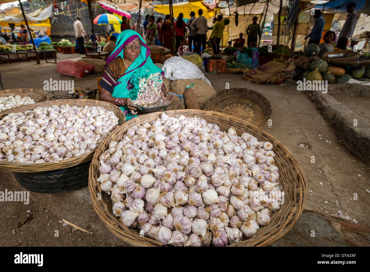 A woman is selling garlic in baskets at the weekly vegetable market Stock Photo, Royalty Free