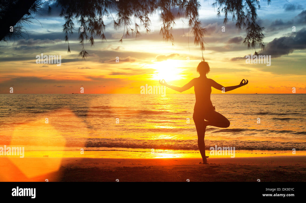 yoga-woman-on-sea-coast-at-sunset-DX3EYC