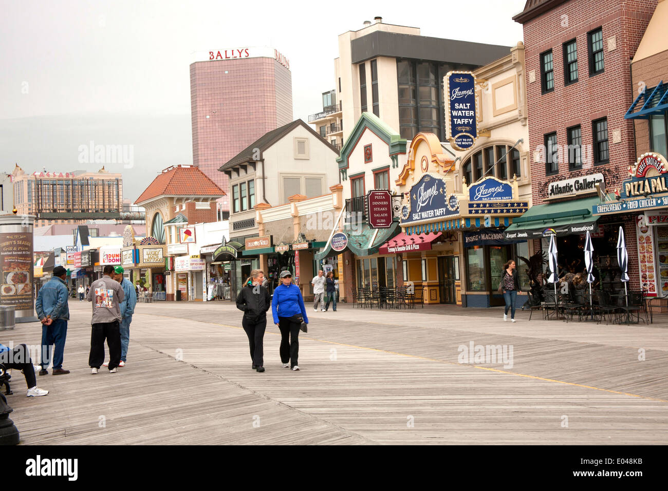 Tourists on Boardwalk in Atlantic City, New Jersey with shops and Stock