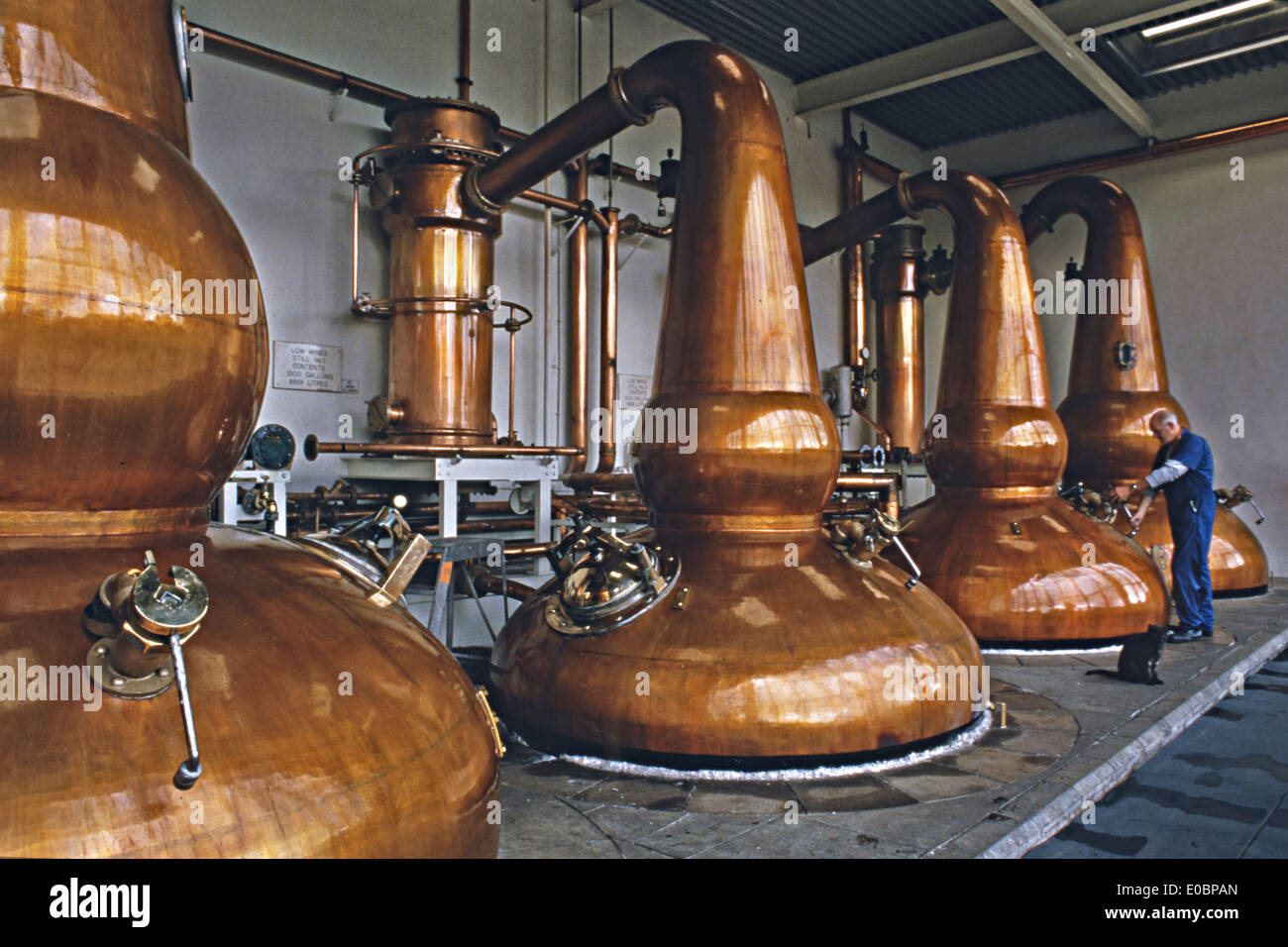 Scottish distillery worker by 4 copper pot kilns Stock Photo, Royalty