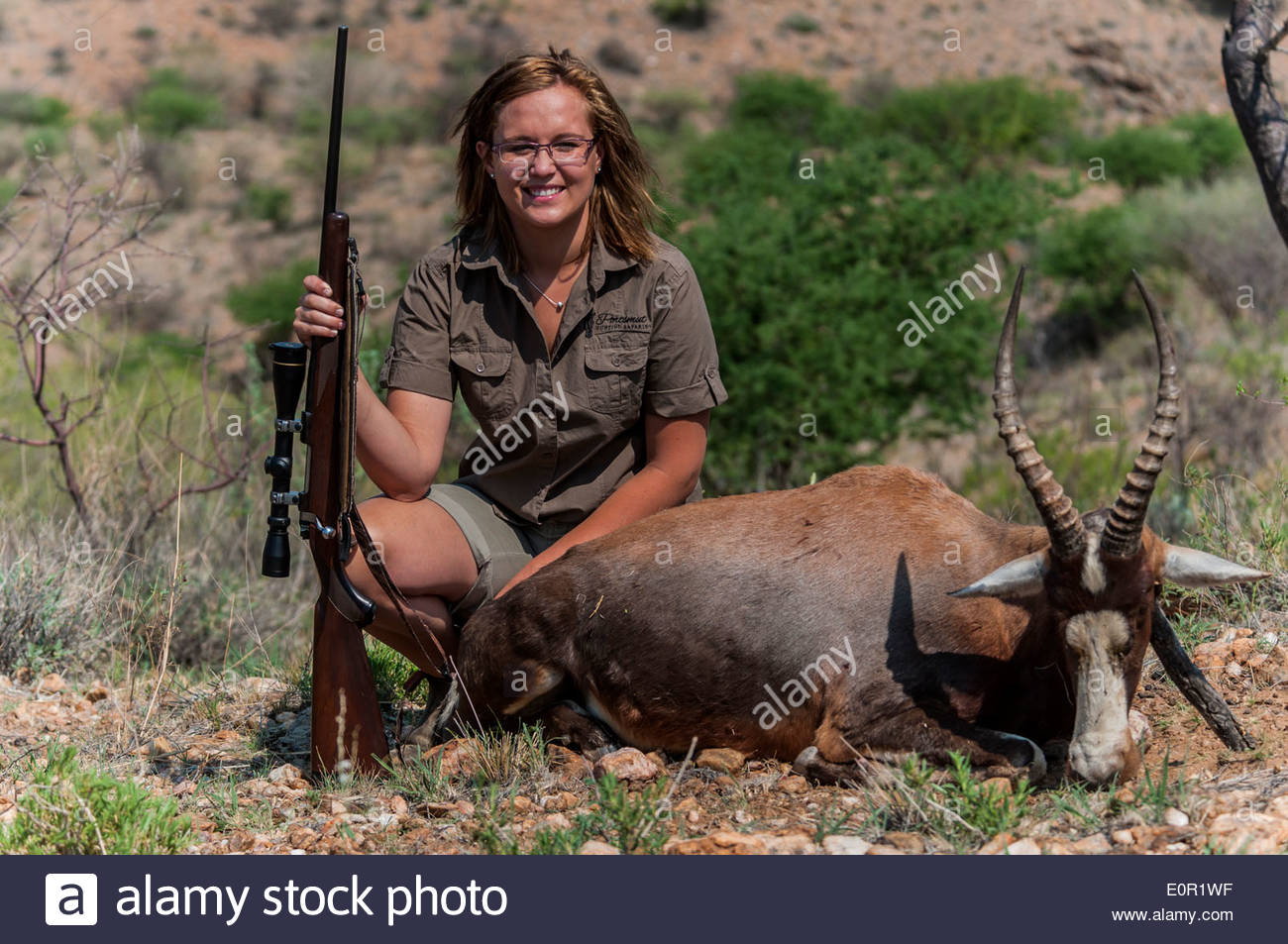 A lady hunter pose with her rifle with which she shot a trophy Stock