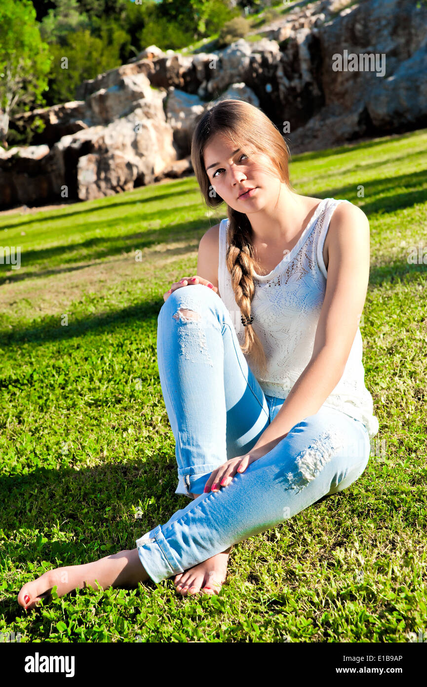 http://c8.alamy.com/comp/E1B9AP/barefoot-girl-in-ripped-jeans-sitting-on-the-grass-in-the-park-against-E1B9AP.jpg