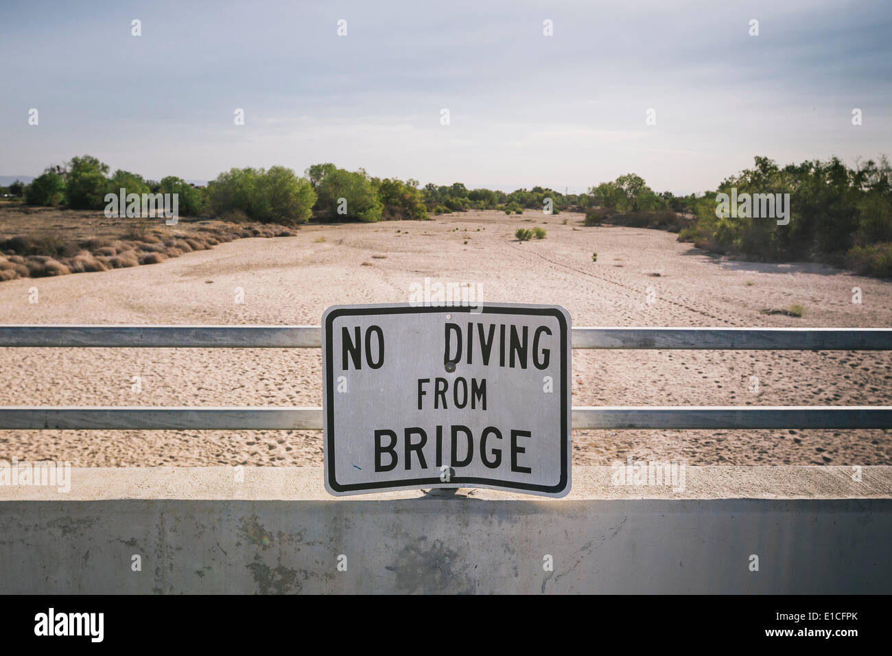 A sign cautions people not to dive from a bridge over the Kern River
