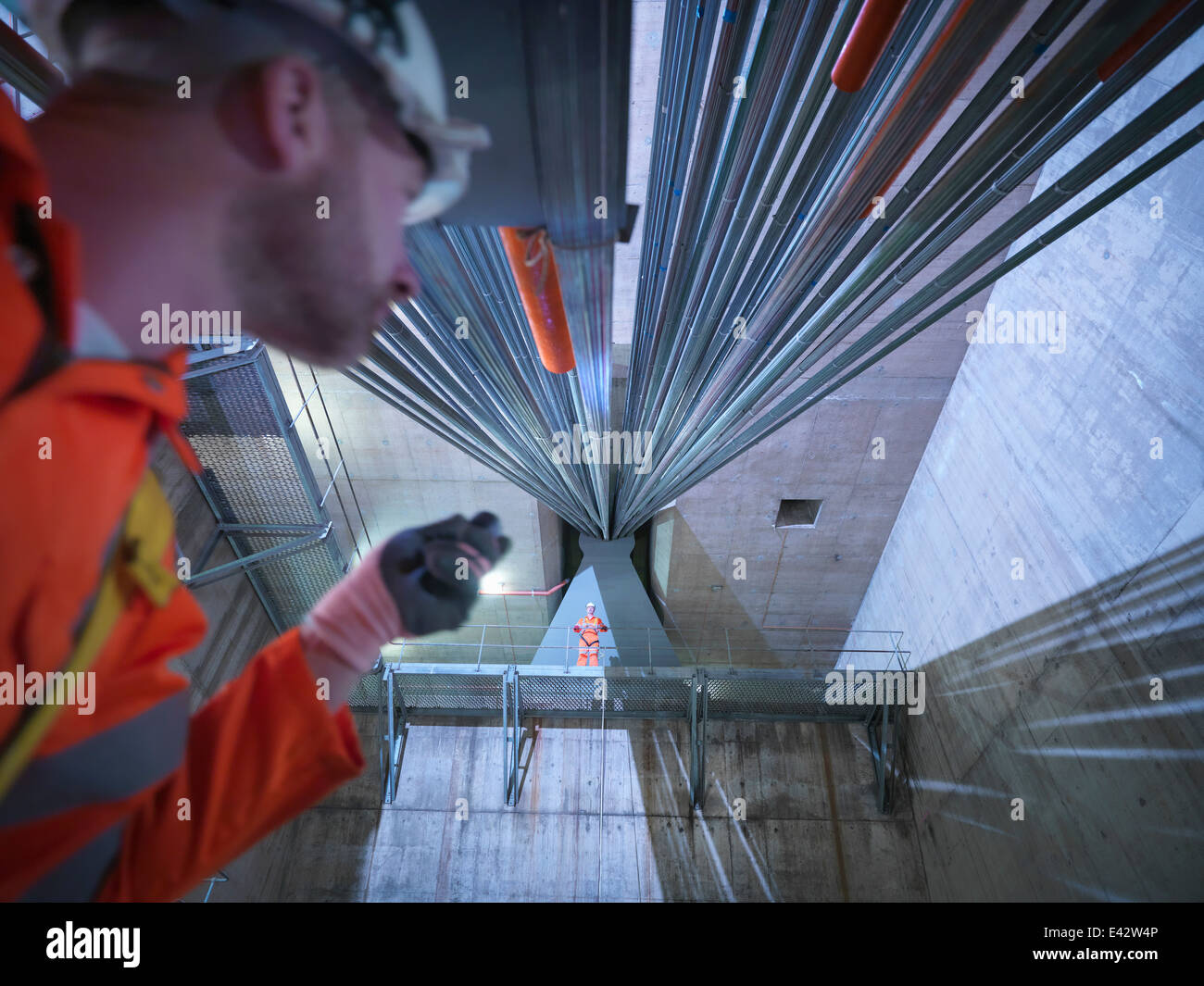 Civil engineers inspecting cable anchorage in suspension bridge, low