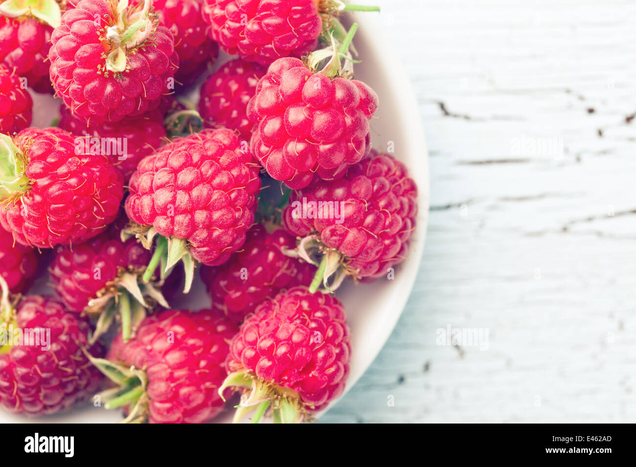 Tasty raspberries in a wooden bowl and a spoon Top view