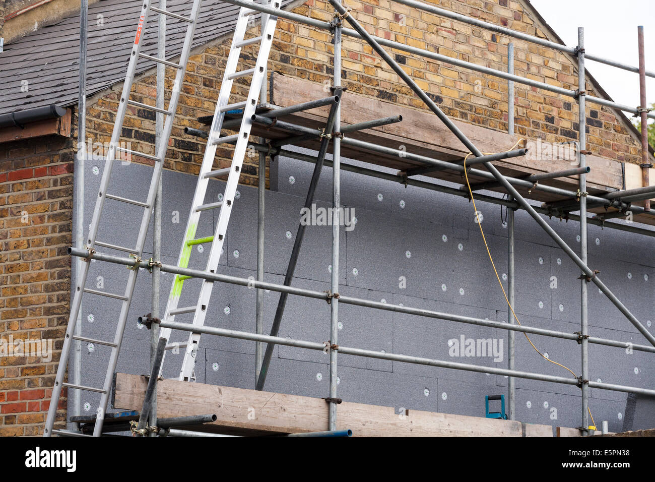 Builders attaching / fitting rigid foam wall insulation sheets Stock