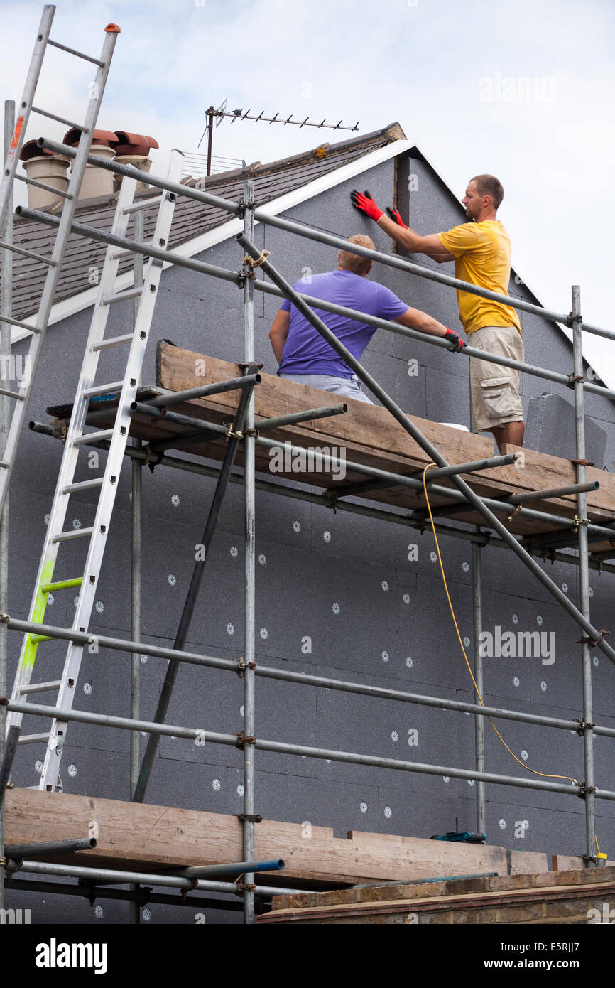 Builders attaching / fitting rigid foam wall insulation sheets Stock