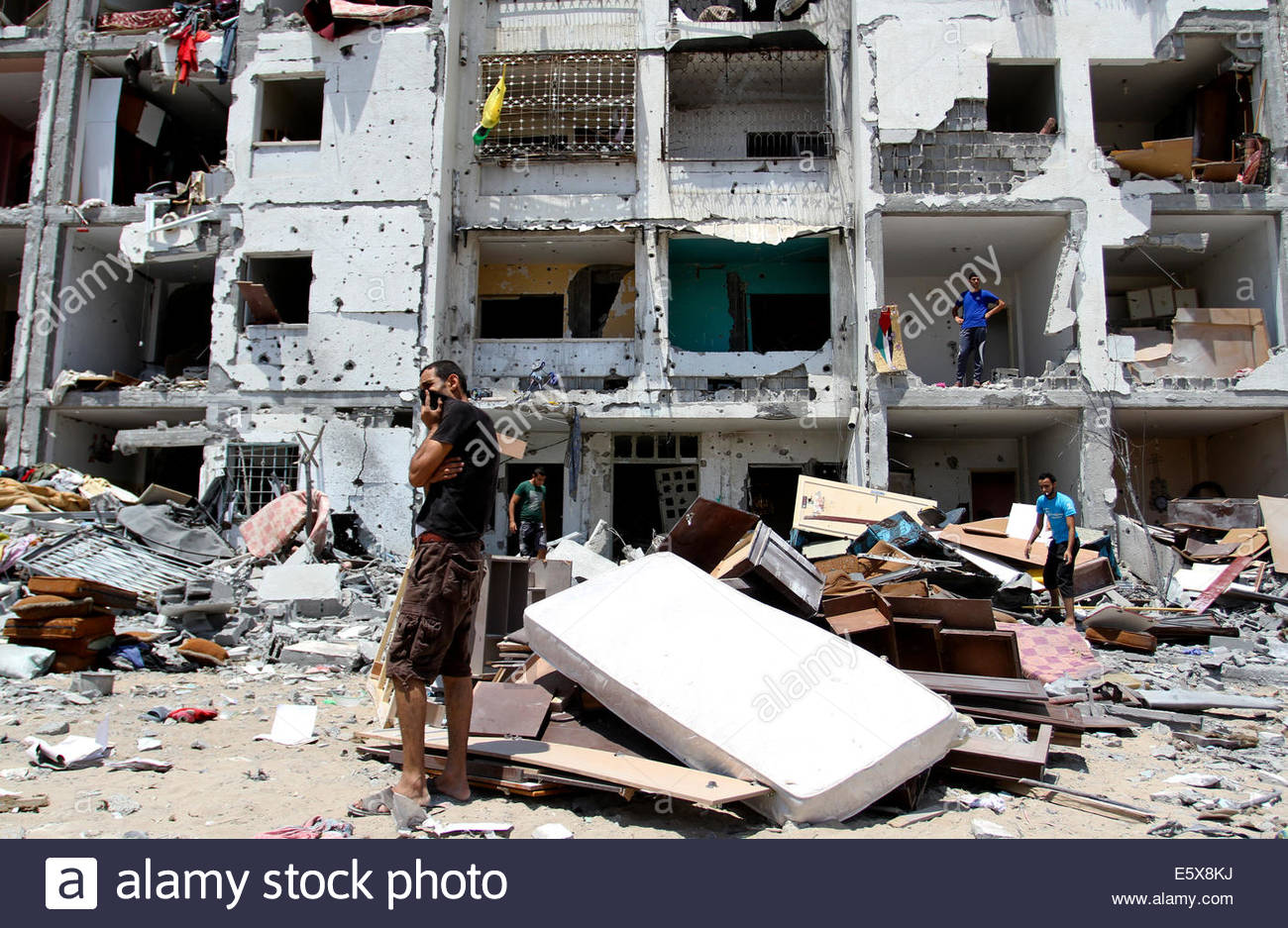 Palestinians inspect in the rubble of their destroyed apartment in a