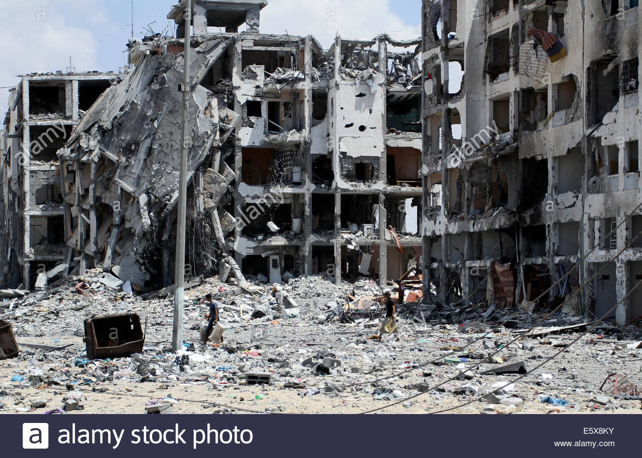 Palestinians inspect in the rubble of their destroyed apartment in a