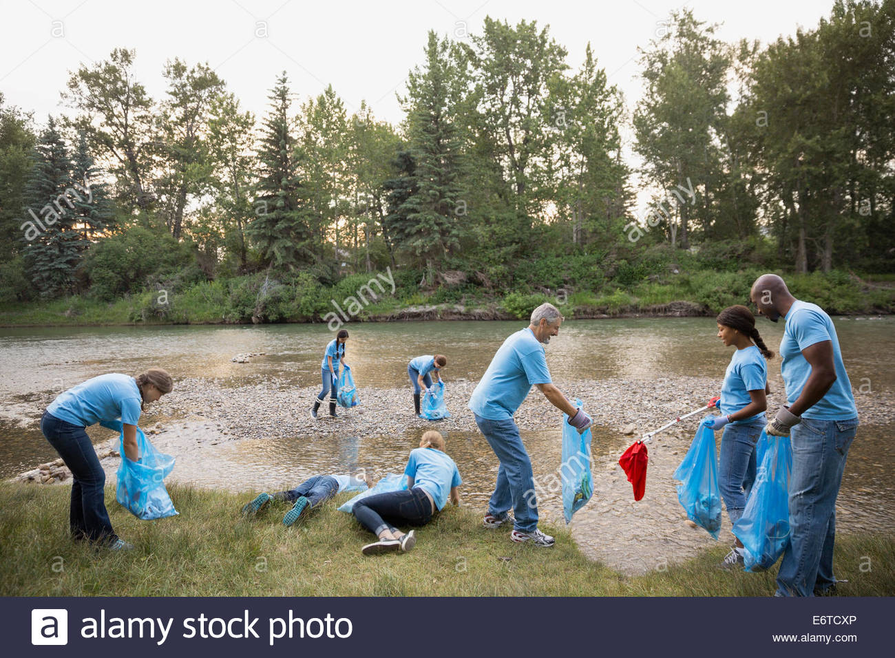 Volunteers picking up garbage at riverbank Stock Photo, Royalty Free