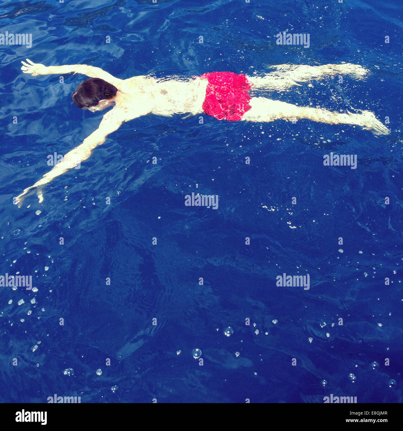 Man floating upside down in blue water Stock Photo, Royalty Free Image