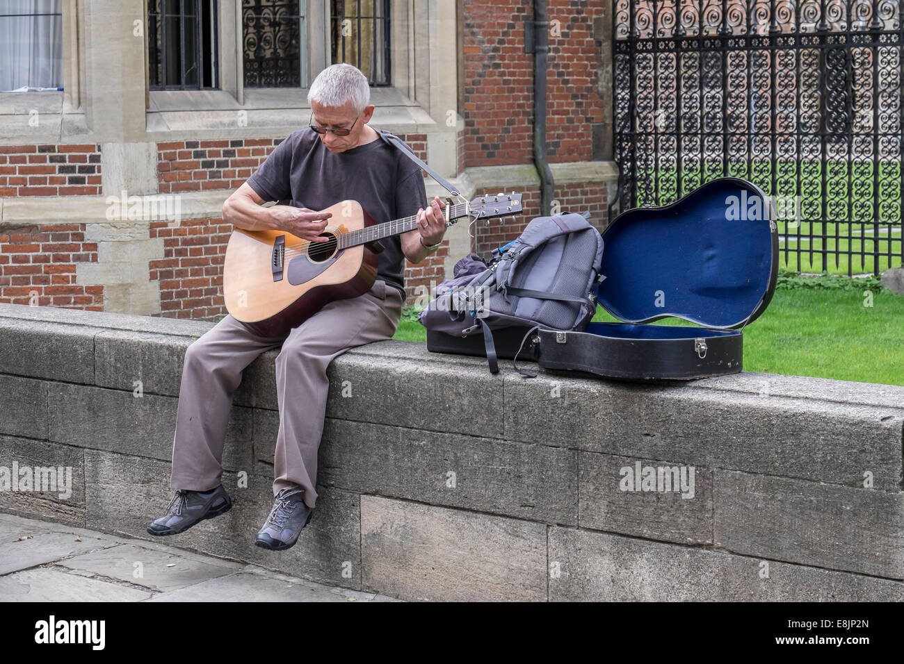 man-busking-on-guitar-sat-on-wall-st-joh