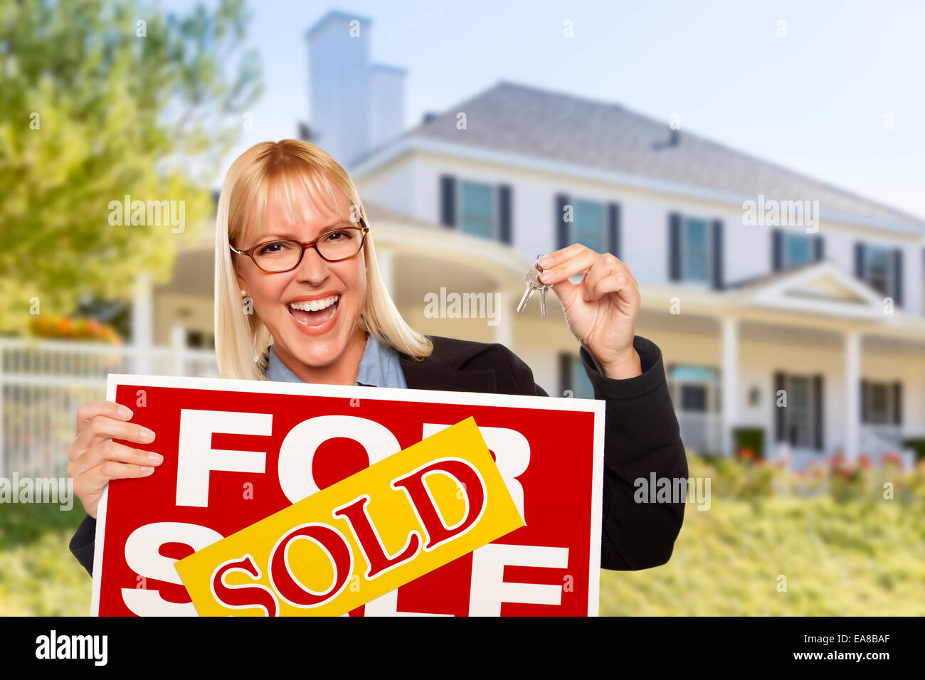 Excited Woman Holding House Keys And Sold Real Estate Sign In Front Of Nice New Home Excited Woman Holding House Keys And Sold Real Estate Sign In Front Of Nice New Home