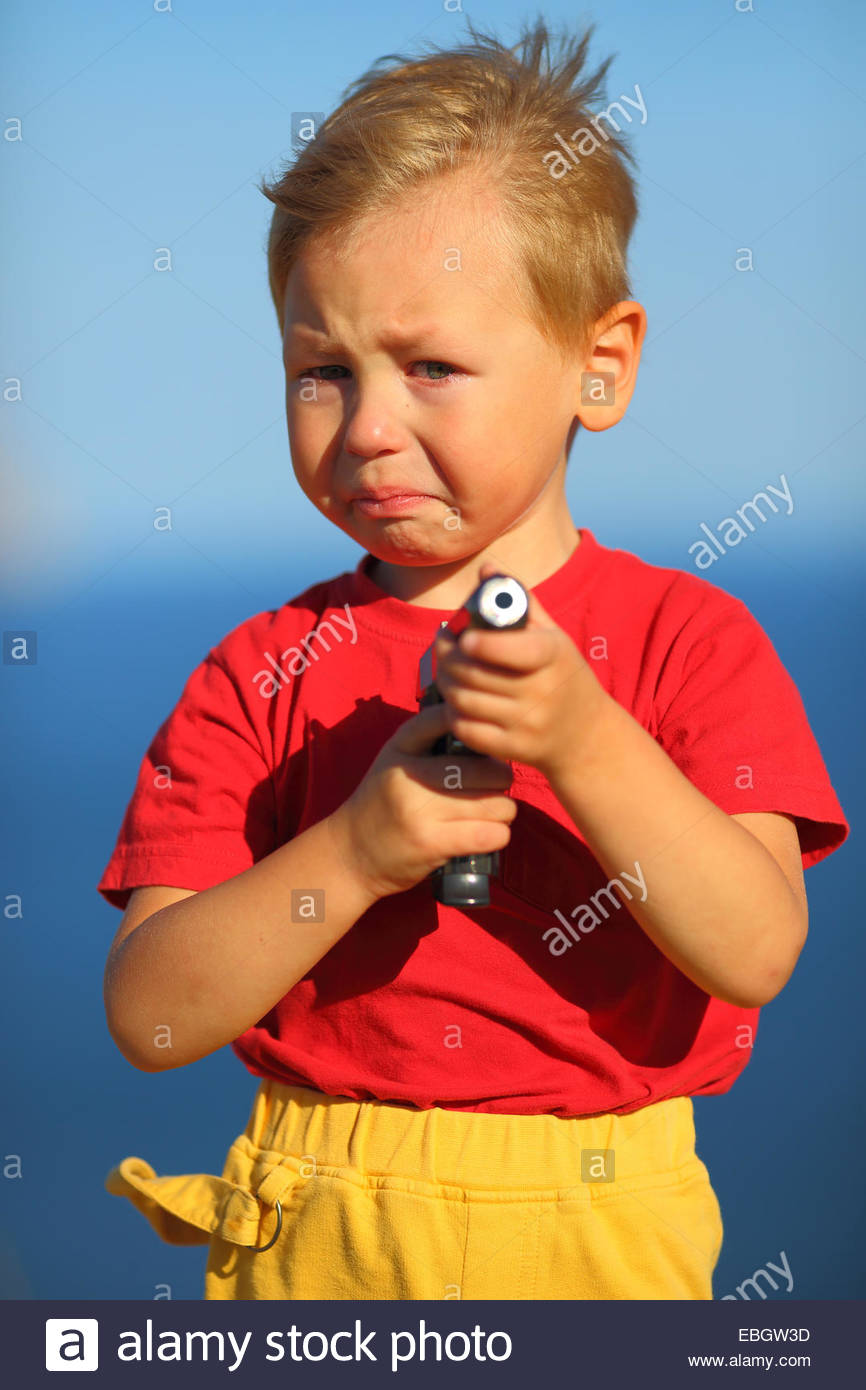 crying boy with a gun on the coast Stock Photo, Royalty Free Image