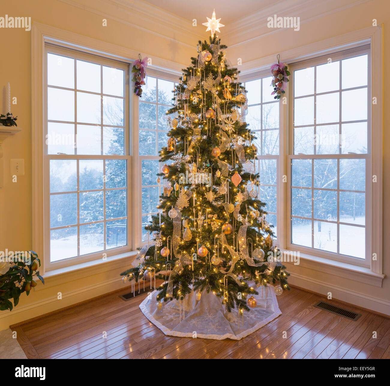 christmas tree in modern home with snow falling outside christmas tree in modern home with snow falling outside