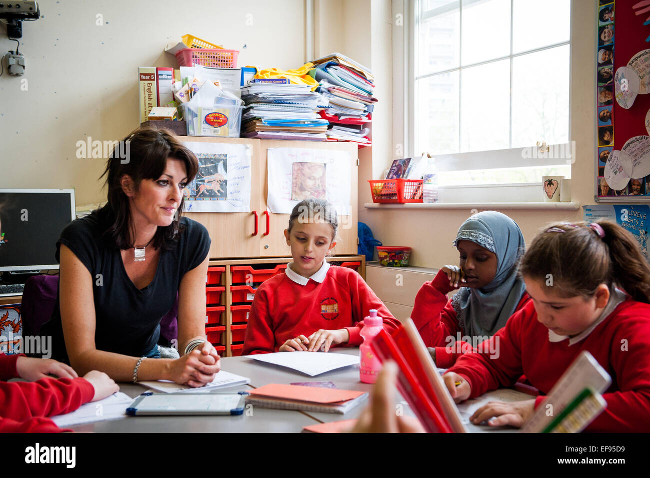 Teacher And Children In Primary School Classroom In London UK Stock teacher-and-children-in-primary-school-classroom-in-london-uk-stock