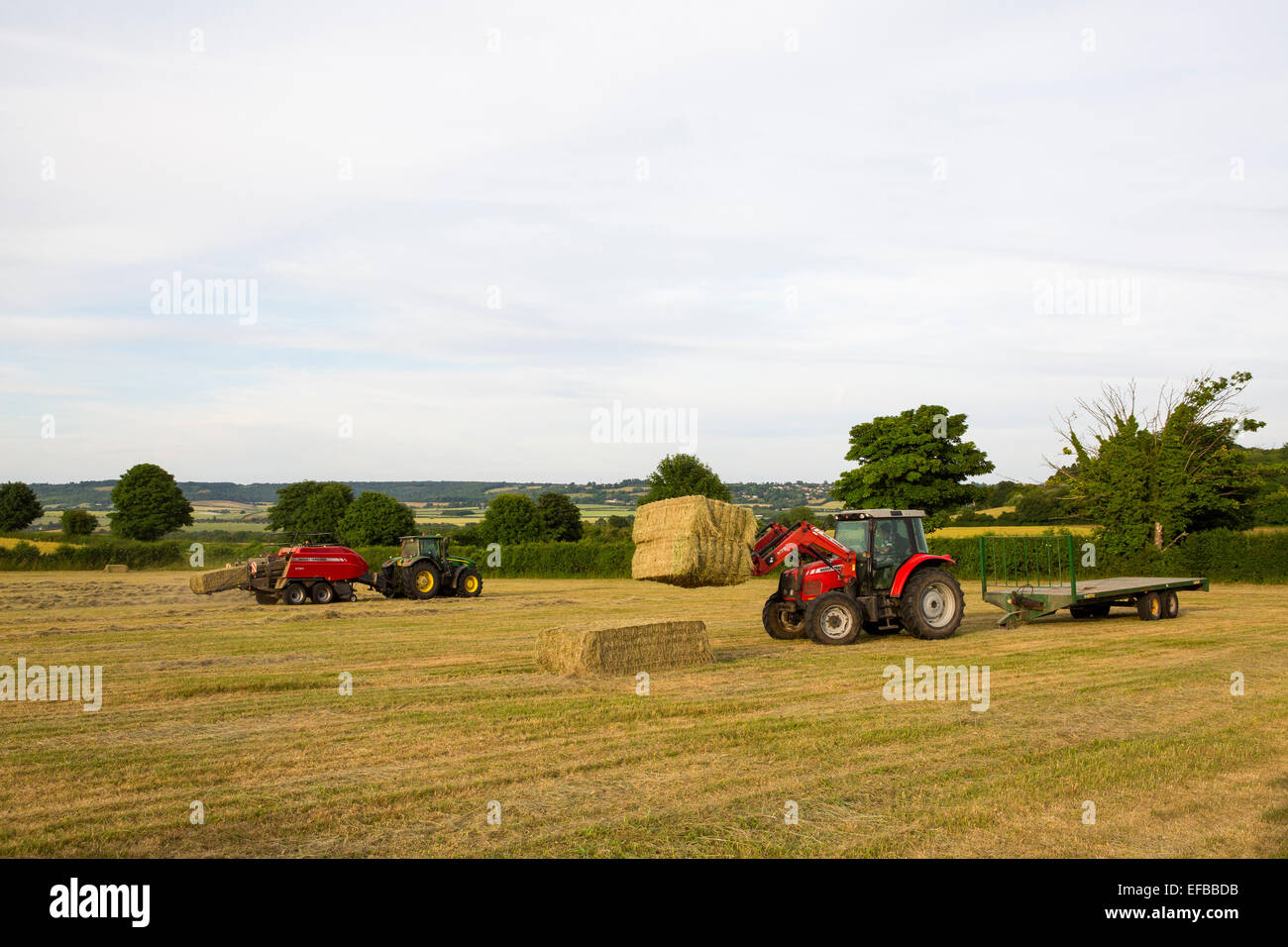 Tractors Baling And Stacking Hay Bales In Field Oxfordshire England