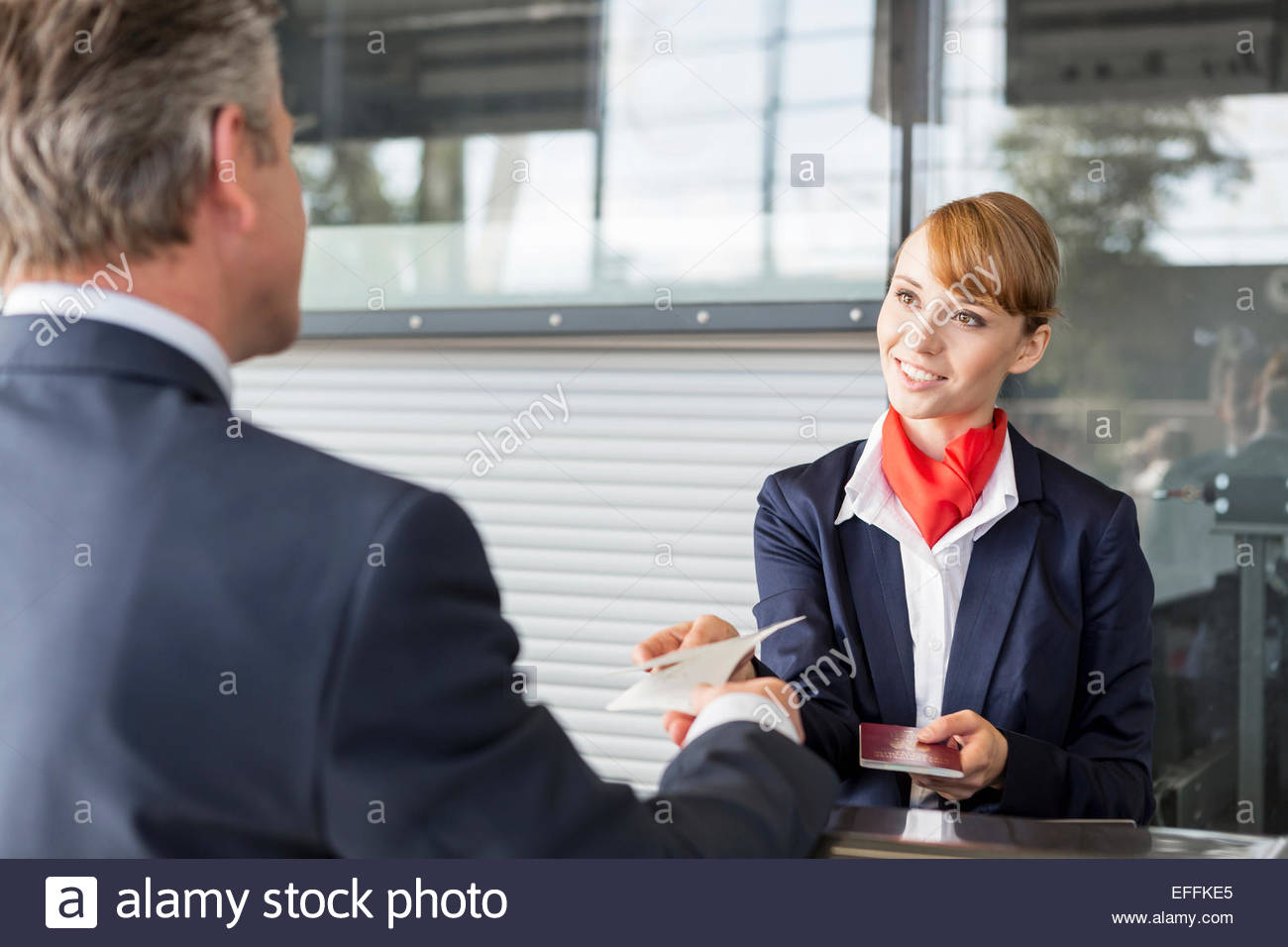 Airport checkin attendant handing out documents to passenger Stock