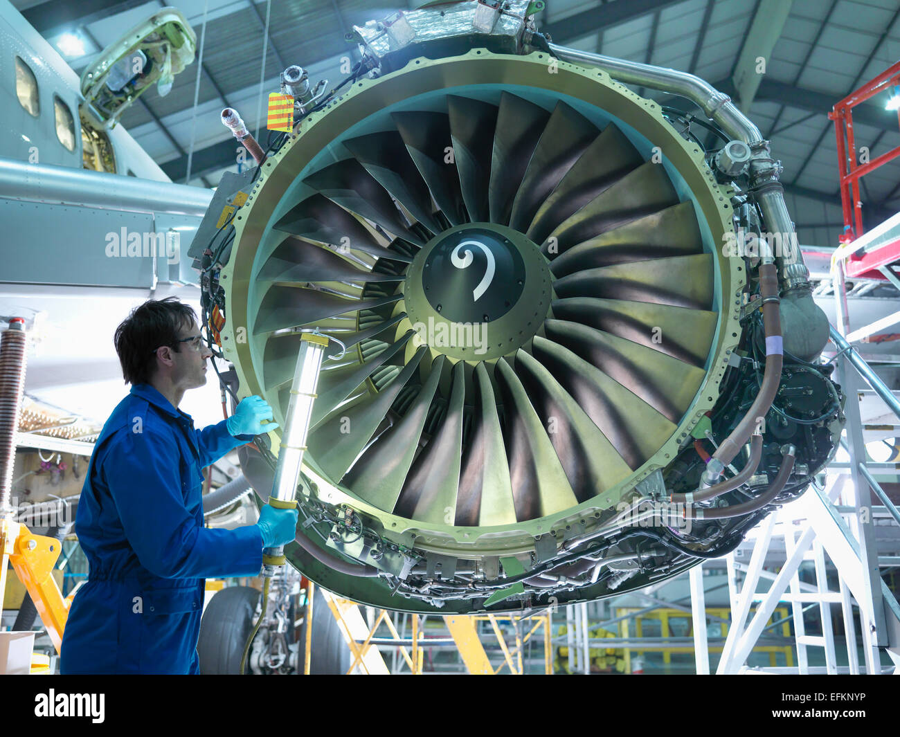 Engineer inspecting jet engine in aircraft maintenance factory Stock