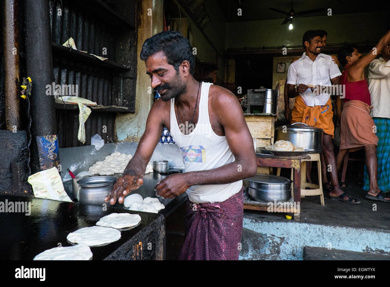 A man makes chapatis and puri on his hot plate in a streetside Stock