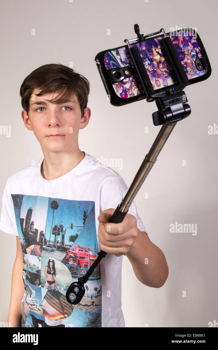 A white teenage boy taking a selfie using a selfie stick Stock Photo