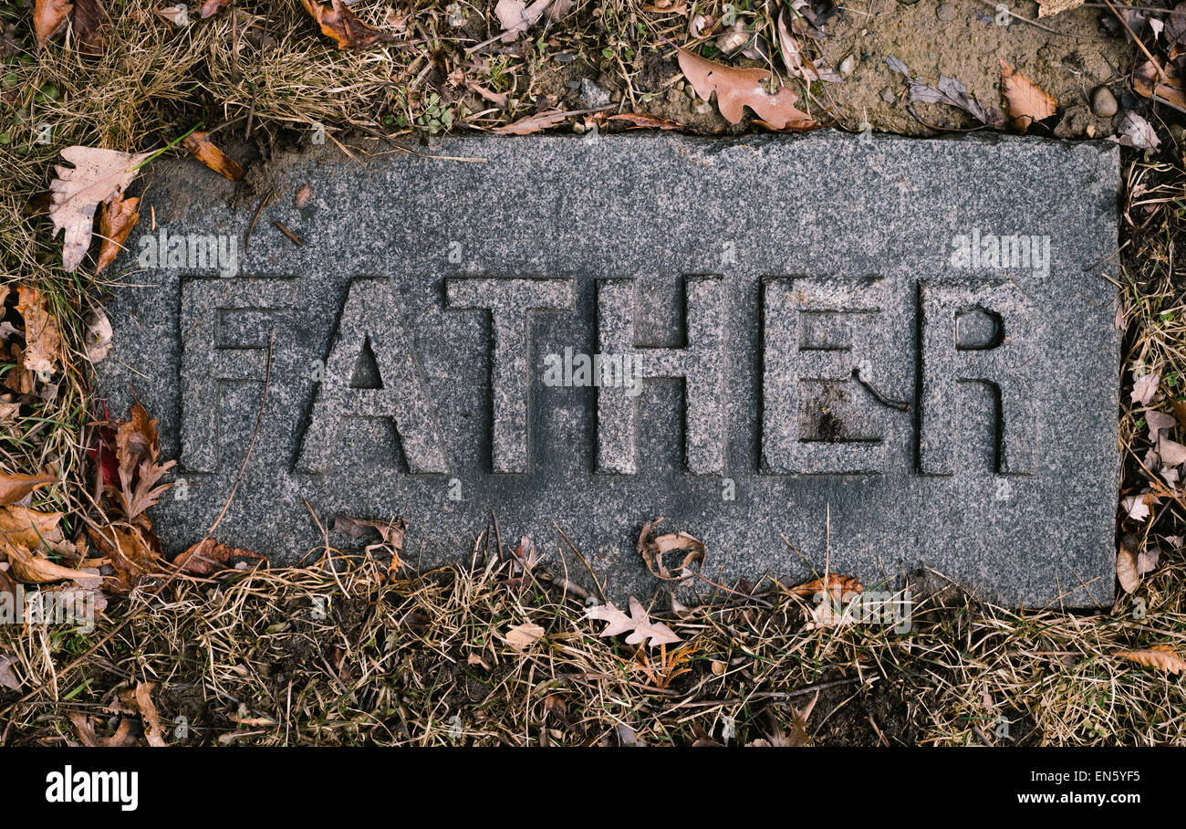 Grave marker or headstone in cemetery with the word Father engraved