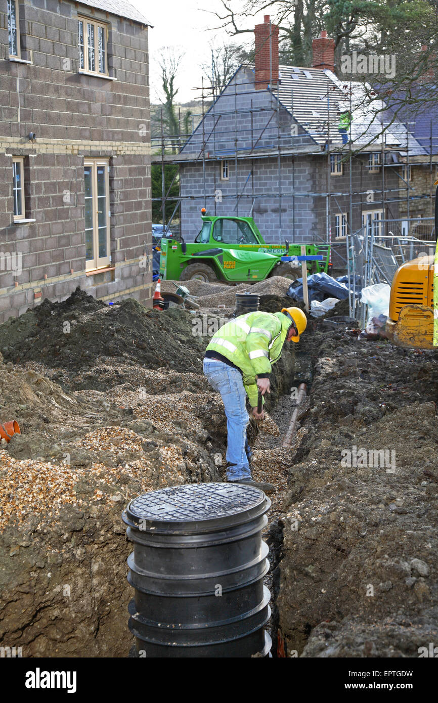A construction worker install plastic underground drainage pipes on a